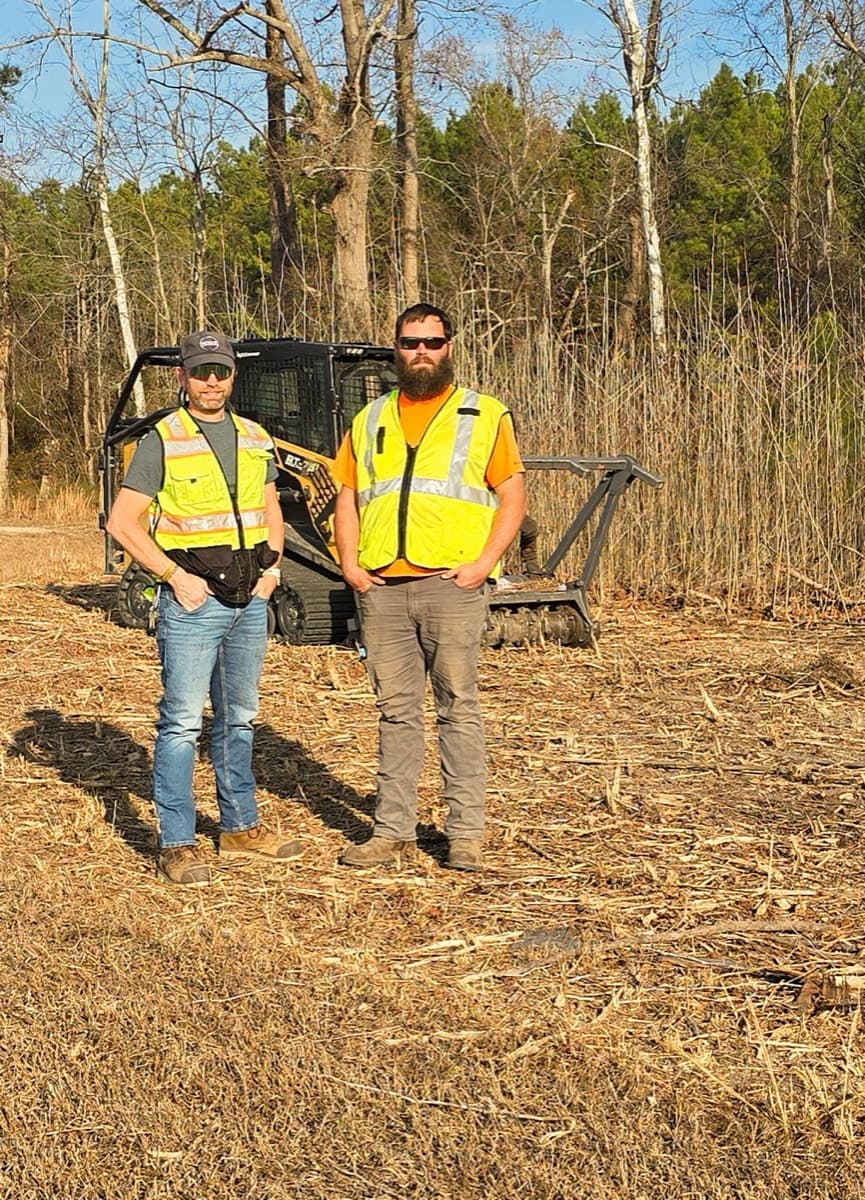 Phillip and Spencer Joyner on a cleared job site with their compact track loader and forestry mulching head